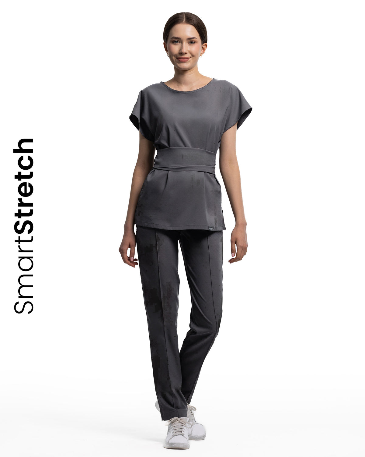 Femeie îmbrăcată în bluza medicală CELESTE grafit SmartStretch cu top cu mânecă scurtă și curea.