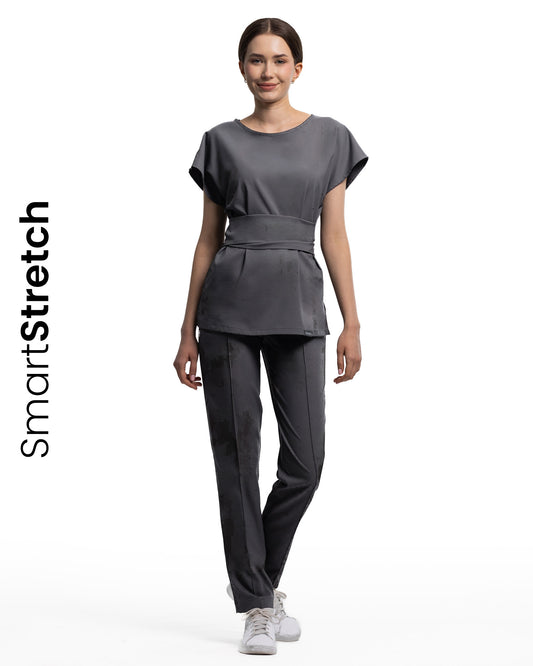 Femeie îmbrăcată în bluza medicală CELESTE grafit SmartStretch cu top cu mânecă scurtă și curea.